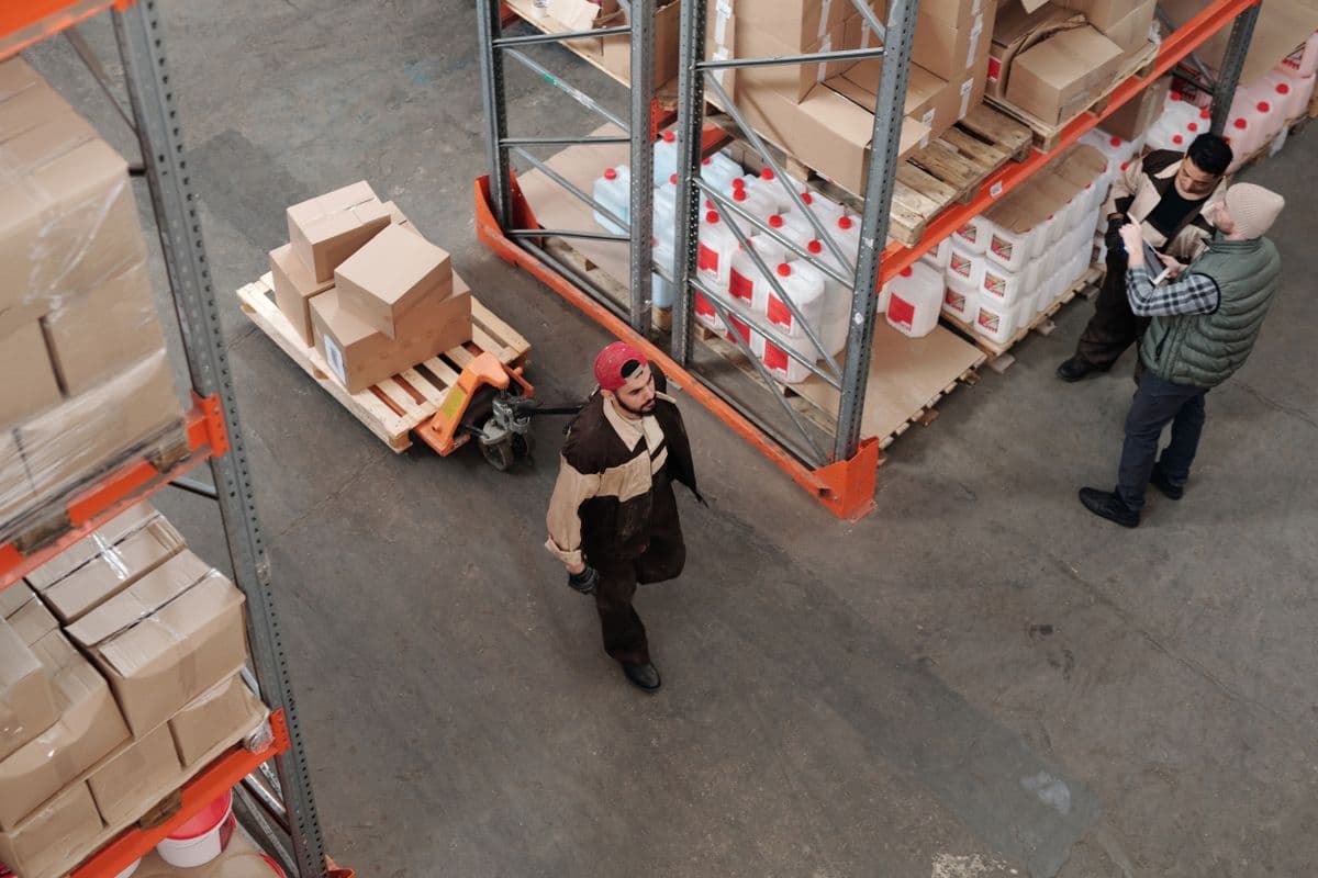 Warehouse team discussing work beside storage racks