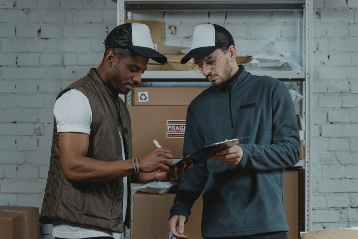 Couriers discussing shipment paperwork in a warehouse