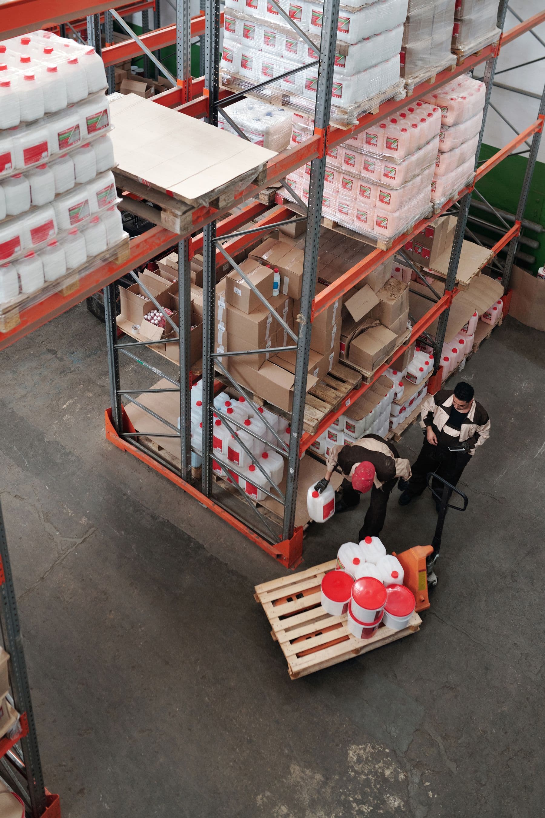 Warehouse team reviewing stock beside distribution shelving